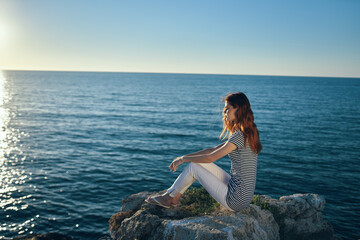 the traveler sits on the beach near the sea in the mountains and sunset