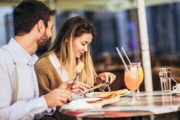 Smiling Couple On Date Enjoying Pizza In Restaurant Together