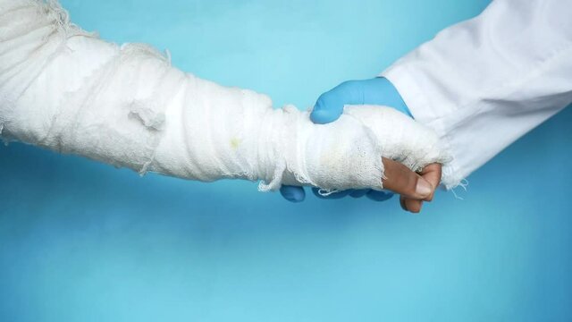 doctor hand in gloves holding injured painful hand with bandage 