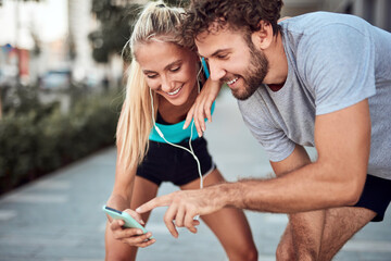 Two sporty young people making pause after jogging and exercising in urban area.