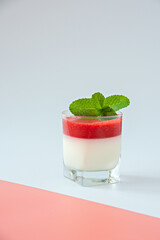 Panna cotta with strawberry sauce in a glass glass.