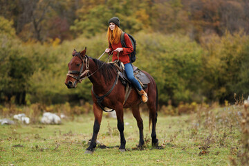 woman hiker with a backpack rides a horse in the mountains nature friendship