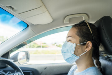 Asian woman with protective face mask driving car.