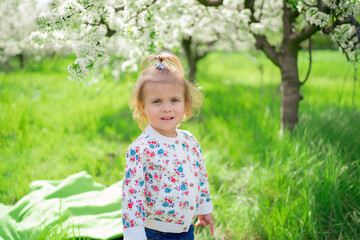 little girl stands in a flowering spring garden. seasonal allergies in children