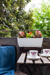 bright small apartment terrace in summer with flowers and coffee table