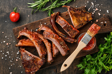 Grilled and smoked pork ribs with barbeque sauce on an old vintage wooden cutting board on old...