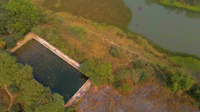 Aerial view of an old abandoned swimming pool surrounded by nature in India.