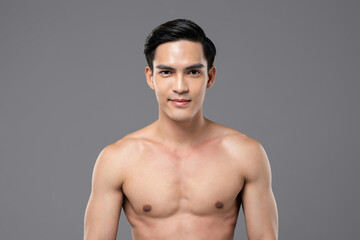 Shirtless handsome Asian man smiling on isolated gray background for beauty and skin care concept