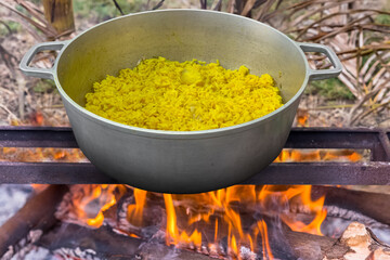 Riz jaune aux pommes de terre sur feu de bois