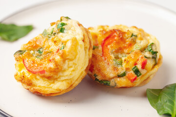 Egg muffins ( bites) and spinach leaves  in a plate on a gray background