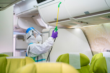 cleaning officer wearing ppe clean aircraft interior, passenger cabin and sprays disinfectant deep cleaning for coronavirus. airline's sanitary measures before use during covid-19 pandemic situation - obrazy, fototapety, plakaty