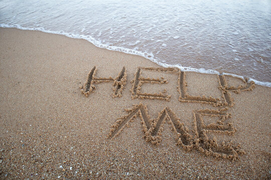 Help signal written on sand beach near sea.