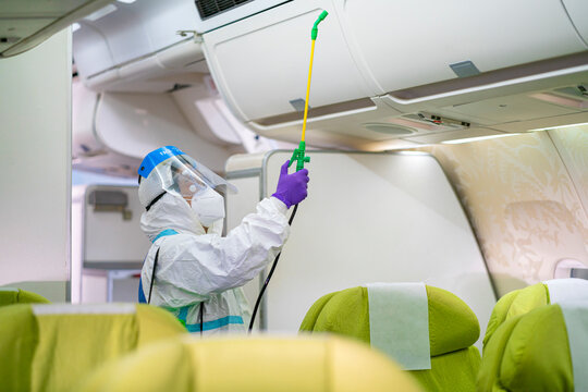 Cleaning Officer Wearing Ppe Clean Aircraft Interior, Passenger Cabin And Sprays Disinfectant Deep Cleaning For Coronavirus. Airline's Sanitary Measures Before Use During Covid-19 Pandemic Situation