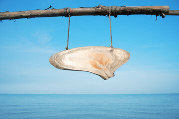 Empty vintage wooden sign hanging on a rope,With a clear sky and sea in the background.