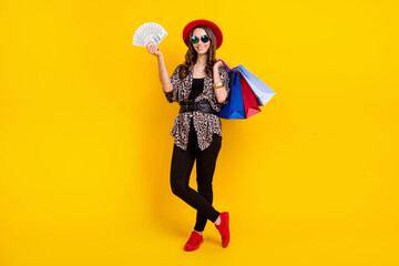Full length photo of brunette happy nice woman hold hand shopping bag money isolated on yellow color background