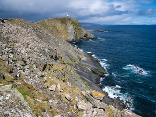 With debris above, steeply inclined, fractured rock strata on Sumburgh Head, south Shetland, UK -...