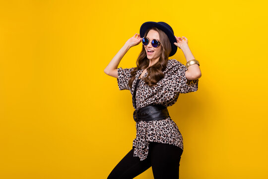 Portrait of attractive chic cheerful girl posing touching hat having fun isolated over bright yellow color background