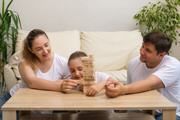 Happy family and cute little girl excites with wooden block game