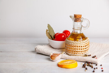 Vegetable oil in a bottle on a towel with tomatoes, lemon, pepper and bay leaf with copy space.