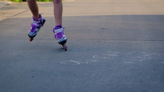 The child is rollerblading on the street. Selective focus.