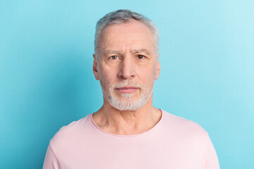 Photo portrait of serious bearded man in pink t-shirt isolated on pastel blue color background