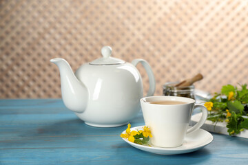 Aromatic celandine tea and flowers on light blue wooden table