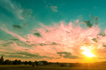 Rural landscape with beautiful gradient evening sky at sunset. Silhouette of houses against sky