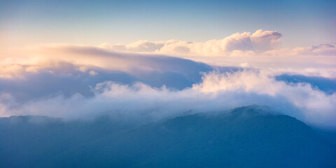 summer landscape on a foggy morning. amazing mountain view in the distance. scenic outdoor scenery. beautiful nature environment background. clouds on the sky above horizon