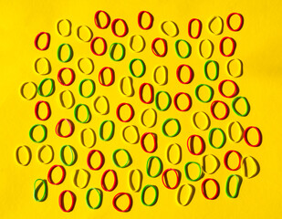 Pattern of colorful rubber bands on yellow background. Office utensils concept. Loom bands. Minimalist background. Office layout or template, office equipment. Circle geometric pattern, vibrant color