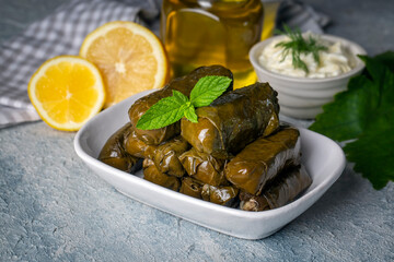 Delicious dolma (sarma) stuffed grape leaves rice, white yogurt sauce. Lebanese dolma sarma on plate. Lebanon turkish greek middle eastern cuisine. (Turkish name; Yaprak sarma)