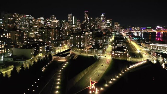 Cinematic 4K drone, after sunset night reveal clip of Olympic Sculpture Park downtown Seattle with illuminated streets and offices looking from South Lake Union in Seattle, Washington during blue hour