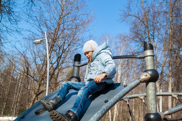 little girl on sunny spring day Smiling and having good time on kids climbing equipment on playground. Portrait of adorable child outdoors on spring day.