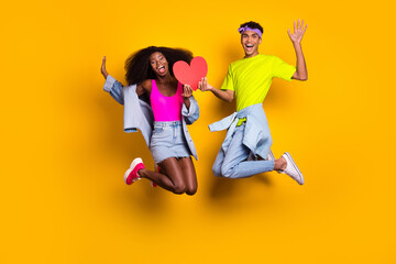 Full length body size view of handsome beautiful couple jumping holding red heart card having fun...
