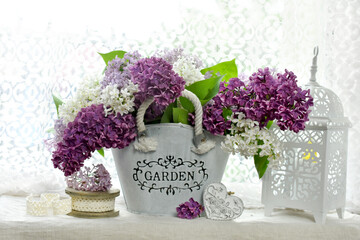 bunch of 3 color lilac in metal basket on window sill