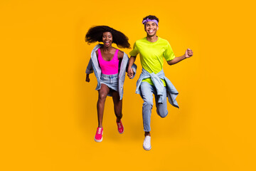 Fototapeta na wymiar Full length body size view of handsome beautiful trendy cheerful couple jumping running isolated on bright yellow color background