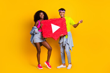 Photo of excited sweet young people wear jeans clothes holding big video recorder sign isolated yellow color background