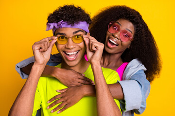 Photo of funny adorable young couple dressed denim outfit sitting back arms ark eyewear isolated yellow color background