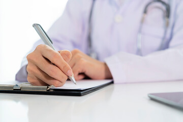 Fototapeta premium Doctor with a clipboard wrote on paper at the desk in the office.