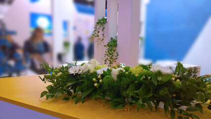 Floristic decor of recreation and networking zone for meeting in expo centre. Green plants and flowers. Business Office interior design. Trade show. Reception Blurred background. Selective focus.