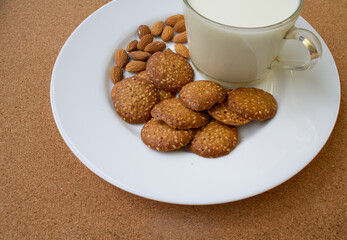 round cookies, nuts on a white plate. glass of milk