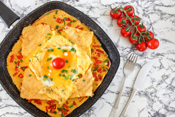 Traditional Delicious omelette with vegetables and Tomato in frying pan, Copy space, Top view, Food Concept, marble pattern background.
