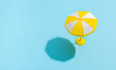 Summer concept. Sun umbrella with sun shadow on blue background. Sun protection concept in summer.