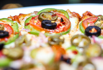 Fresh and Tasty pizza with vegetables, tomato, onion and olives isolated on white plate. Close view.