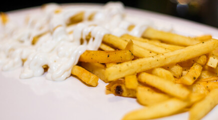 Close up of French fries with mayonnaise in a plate.