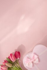 Bouquet of pink tulips and gift box on pink background. Copy space. Vertical orientation.