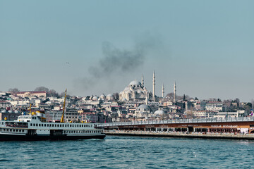 Fototapeta premium Turkey istanbul 03.03.2021. Old and ottoman yeni Cami mosque in istanbul turkey during morning with ancient galata bridge pedestrian ferry in golden horn.