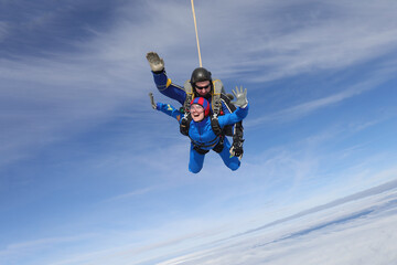 Skydiving. Tandem jump. A young woman and her instructor are in the sky. 
