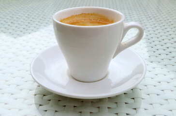 Closeup a cup of hot frothy coffee isolated on white table	
