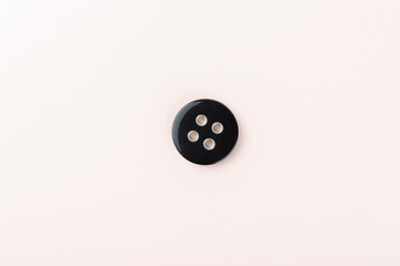 Top view of a black plastic button with metal inserts in the holes.