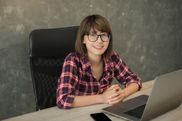 Portrait of beautiful young woman is looking at camera and smiling while working in office.